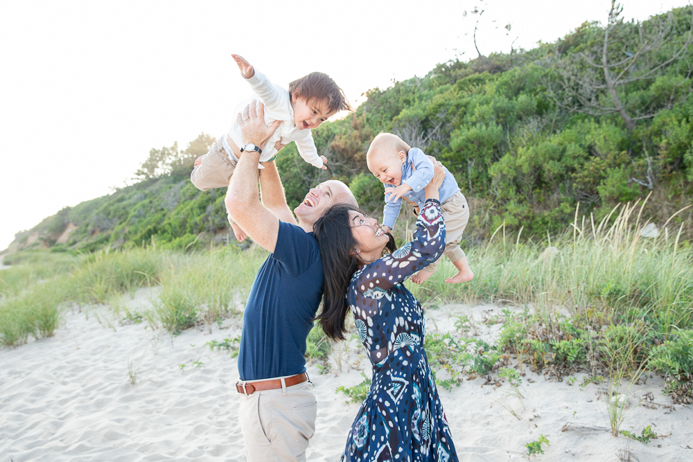 Parents lift toddlers into the air on the beach in Montauk, NY
