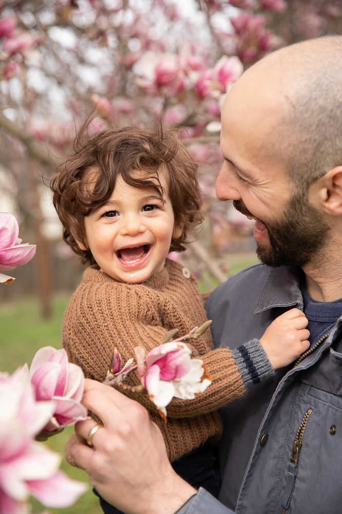 father and baby boy smile with a magnolia tree framing them