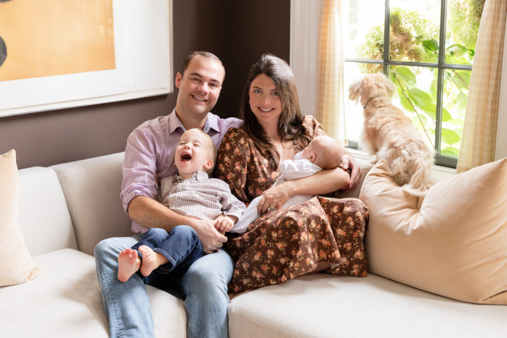 Family photos at home in the Hudson Valley with a family snuggled on the couch with their toddler, newborn and dog.