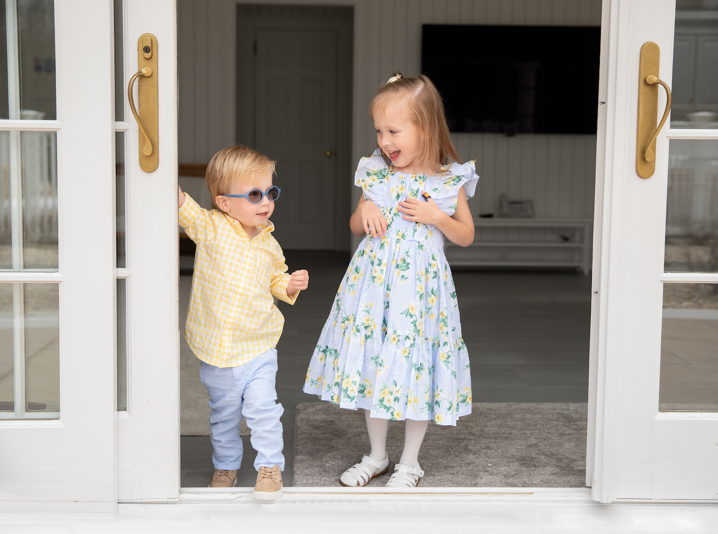 Children stand in the door frame laughing with each other during a family photography session in Greenwich, CT